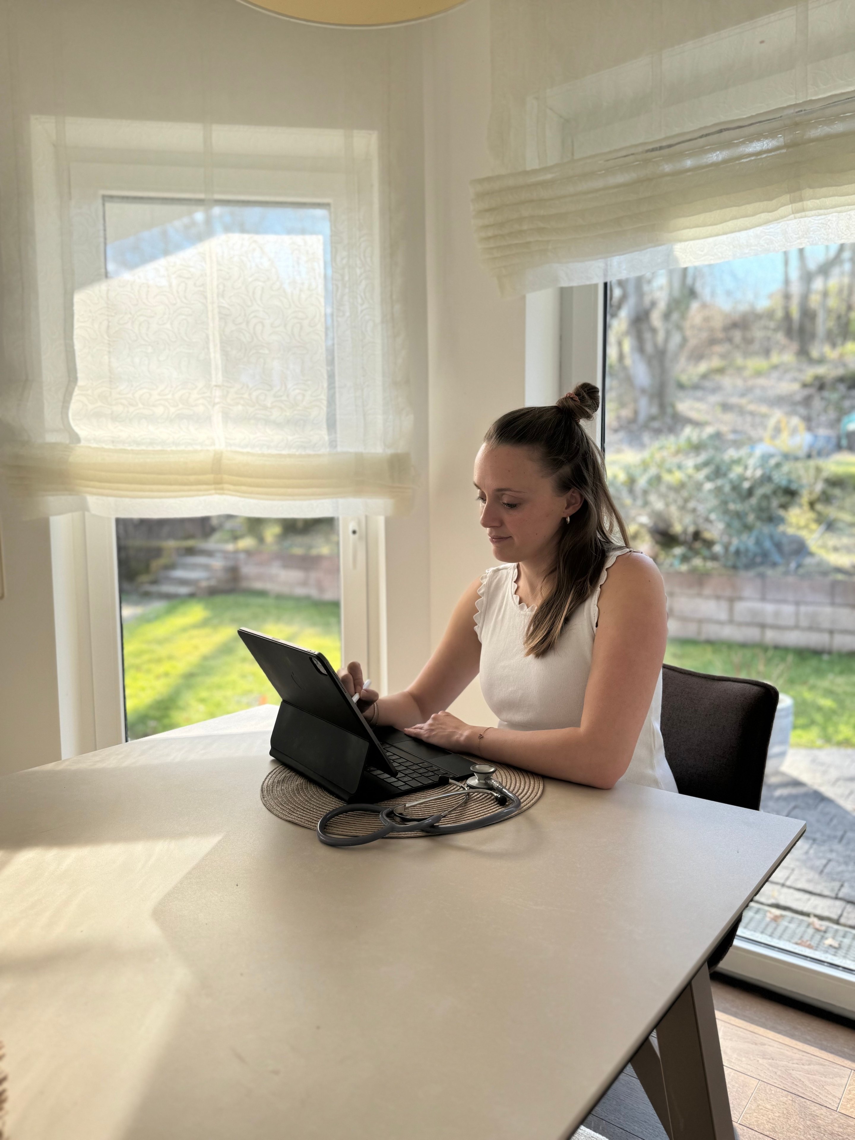 Dr. Pauline Ramisch am Schreibtisch mit Tablet und Stethoskop